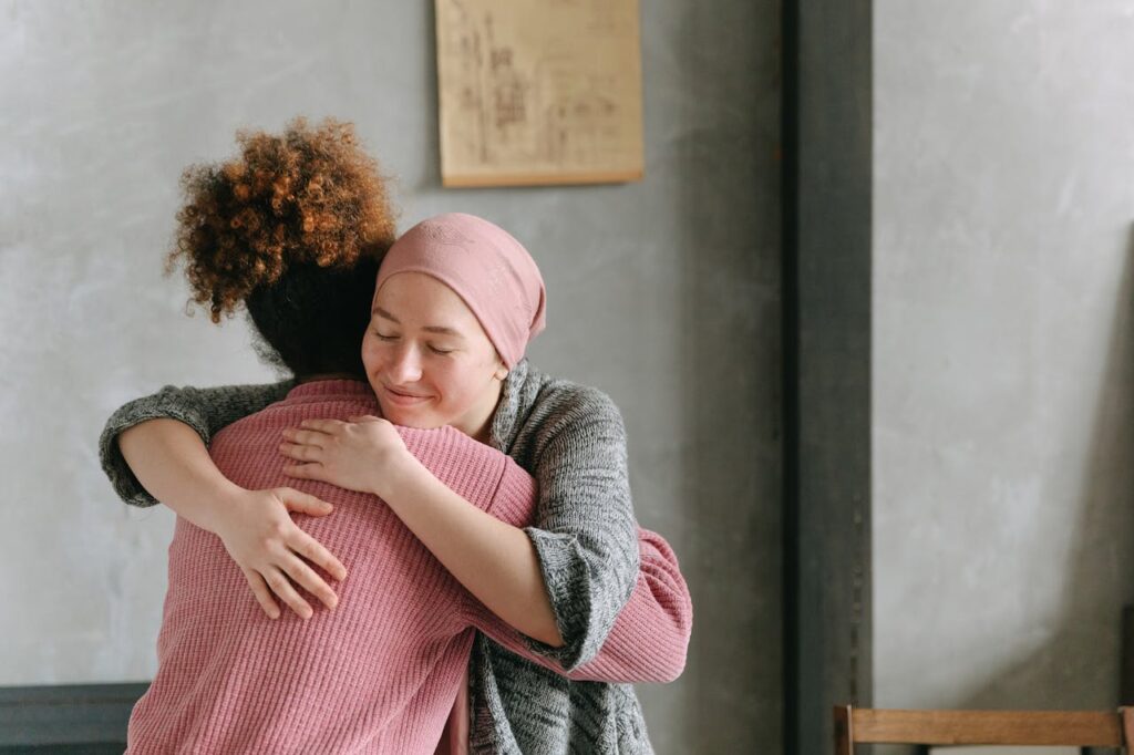 Two women embracing each other with warmth and love, symbolizing support and care indoors.